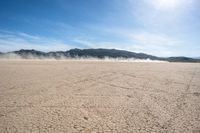 a dirt field that is barren with no cars in it and a mountain behind it