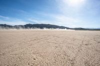 a dirt field that is barren with no cars in it and a mountain behind it