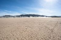 a dirt field that is barren with no cars in it and a mountain behind it