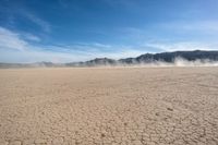 a large open area with desert area with a mountain in the back ground and blue sky above