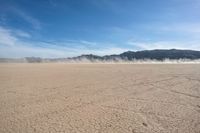 a large open area with desert area with a mountain in the back ground and blue sky above