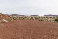 a dirt field with shrubs and bushes on it's surface in the middle of the desert