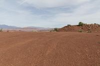 a dirt field with shrubs and bushes on it's surface in the middle of the desert