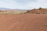 a dirt field with shrubs and bushes on it's surface in the middle of the desert