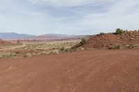 a dirt field with shrubs and bushes on it's surface in the middle of the desert