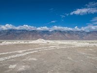 this is an image of some clouds in the sky over a desert field and mountain range