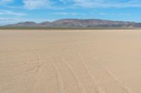 the sand looks like an unpaved beach under a blue sky with mountains in the background