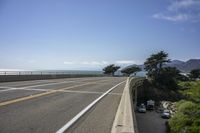 view of ocean from bridge of beach side street and road side area, with car parked next to it