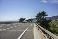 view of ocean from bridge of beach side street and road side area, with car parked next to it