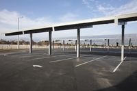 parking lot covered in a long line of poles with a table set up beneath the canopy