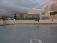 a street sign in a empty parking lot under clouds that are setting in the sky