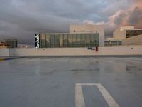 a street sign in a empty parking lot under clouds that are setting in the sky