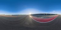 a fish eye view of a motorcycle track with people riding it and another person standing below it