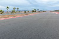 a photo of a dirt race track with sun setting in the distance of the track