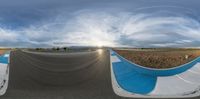 a fisheye view shows some people skateboarding on the street in front of an empty field