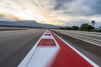 a photo of a dirt race track with sun setting in the distance of the track