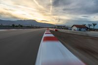 a photo of a dirt race track with sun setting in the distance of the track