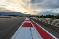 a photo of a dirt race track with sun setting in the distance of the track