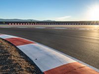 a photo of a dirt race track with sun setting in the distance of the track