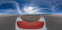 a view of a racetrack with a big curve and the sun above it and clouds in the sky