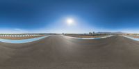 the camera pano lens captures a view of a racetrack and a desert setting with a fence in front