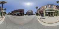 this is an 360 - view picture of a street with palm trees in front of buildings