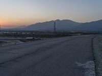 an empty city street has mountains in the distance with no cars on it, and a stop sign near it