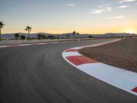 a photo of a dirt race track with sun setting in the distance of the track