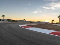 a photo of a dirt race track with sun setting in the distance of the track