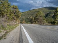 a person on a bike rides down the road with mountains in the distance along side of it