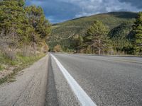 a person on a bike rides down the road with mountains in the distance along side of it