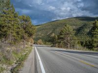 a person on a bike rides down the road with mountains in the distance along side of it