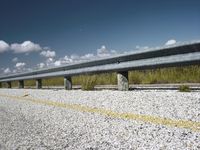 a line of concrete barriers with grass in the background and clouds above them on the road