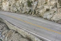 a road in the mountains with a large cliff face and road markings on it on side of cliff