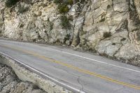 a road in the mountains with a large cliff face and road markings on it on side of cliff