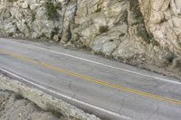 a road in the mountains with a large cliff face and road markings on it on side of cliff