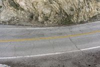 a road in the mountains with a large cliff face and road markings on it on side of cliff