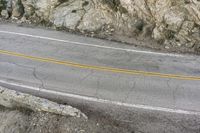 a road in the mountains with a large cliff face and road markings on it on side of cliff