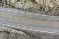 a road in the mountains with a large cliff face and road markings on it on side of cliff