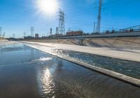 the empty street and dirt of a freeway under a blue sky with power lines overhead