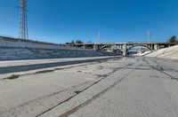 the empty street and dirt of a freeway under a blue sky with power lines overhead