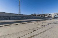 the empty street and dirt of a freeway under a blue sky with power lines overhead