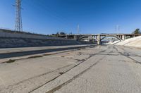 the empty street and dirt of a freeway under a blue sky with power lines overhead