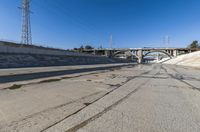 the empty street and dirt of a freeway under a blue sky with power lines overhead