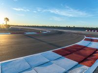 a photo of a dirt race track with sun setting in the distance of the track