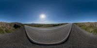 a 360 - angle view of a road with the sun in the background and mountains behind it