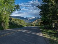 the road winds up on the mountainside on a sunny day with beautiful clouds and trees