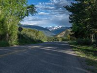 the road winds up on the mountainside on a sunny day with beautiful clouds and trees