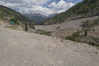 the road is empty with trees and mountains behind it, and the gravel has not been raked