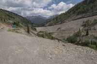 the road is empty with trees and mountains behind it, and the gravel has not been raked